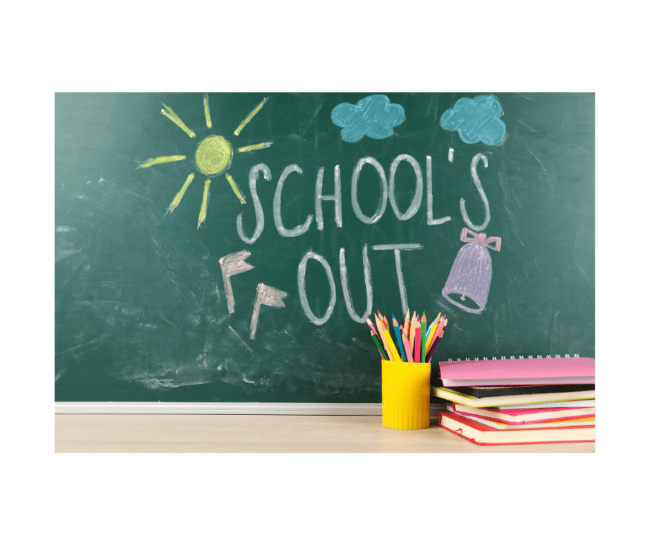Blackboard with a yellow sun and text that says school's out. Yellow up with pencils and some workbooks on a teachers desk.