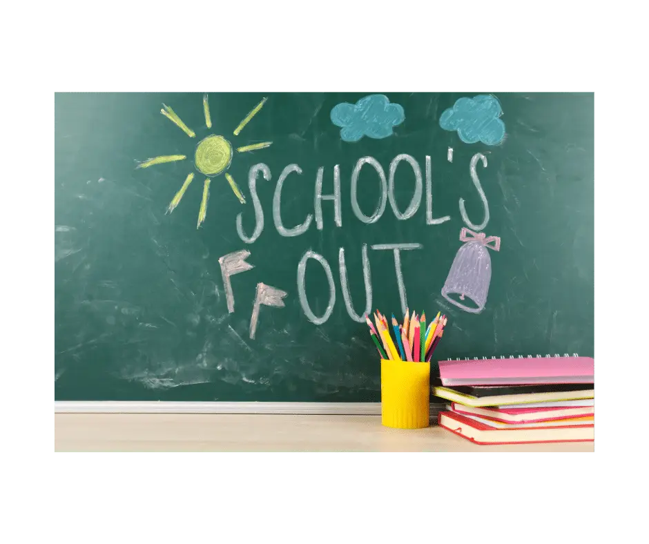 Blackboard with a yellow sun and text that says school's out. Yellow up with pencils and some workbooks on a teachers desk.