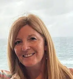 Photo of Dr Ges Gregory, smiling with the sea behind her