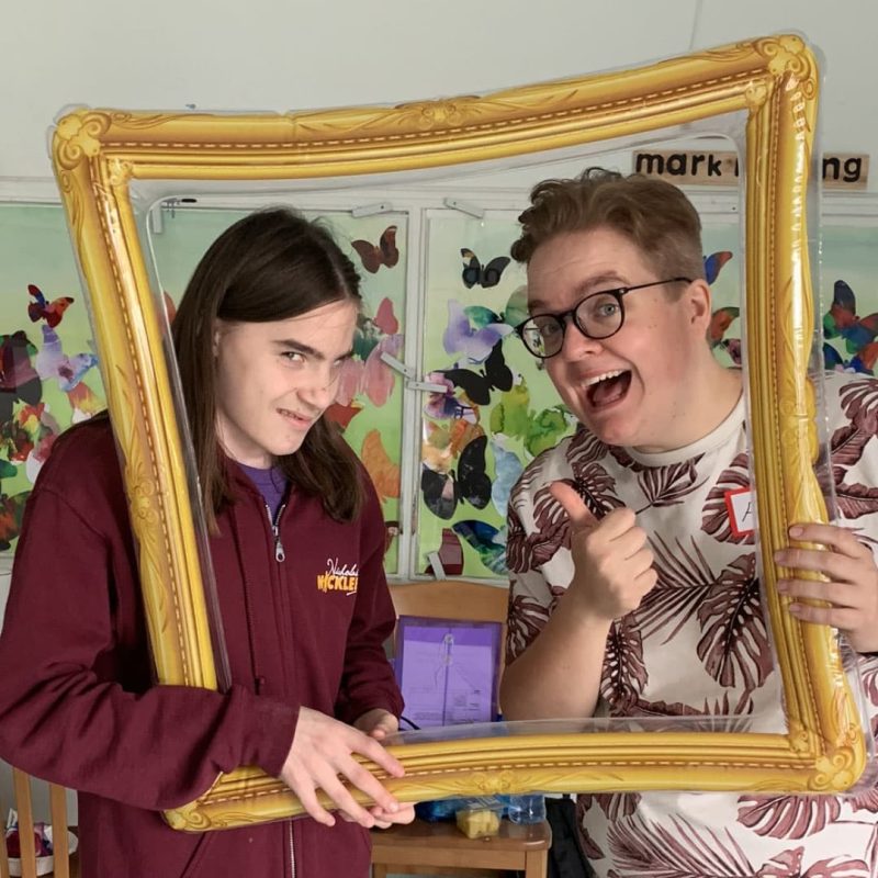 Adult and child with FASD smiling behind inflatable picture frame