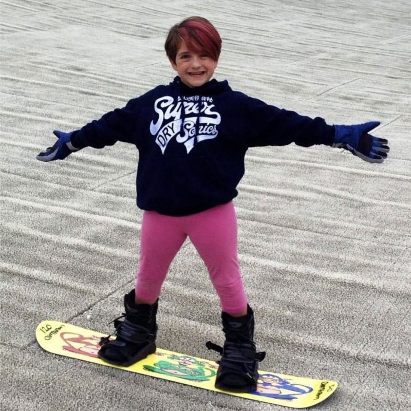 Girl on snowboard smiing at camera