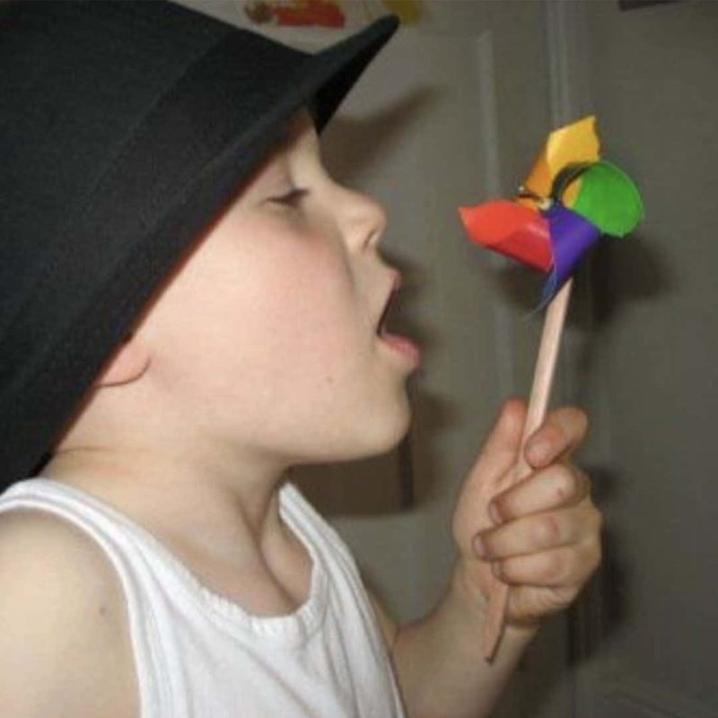 boy blowing a pin wheel