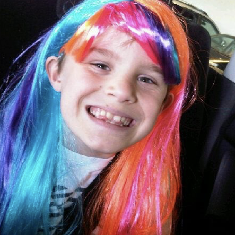 boy wearing a colourful wig smiling at the camera
